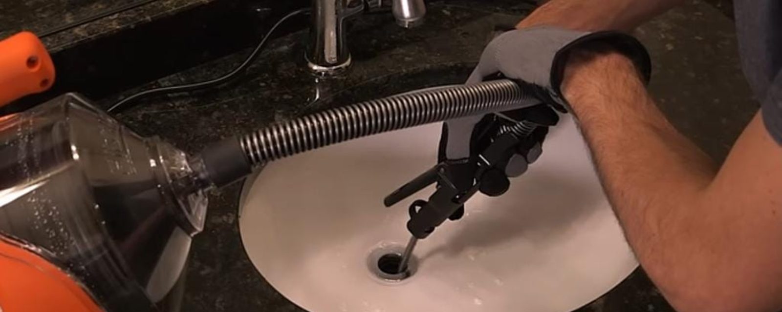 Plumber feeding a drain snake into a sink drain