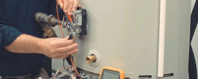 Technician testing the wiring on a gas water heater with a multimeter
